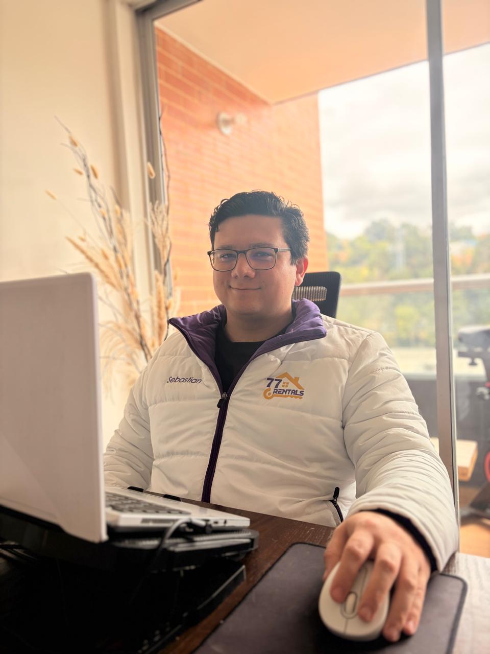 Sebastian working at his desk wearing a 77Rentals branded jacket